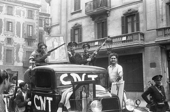 Αναρχικοί και αστυνομικοί στους δρόμους της Βαρκελώνης, κρατώντας πίνακα με αλληγορική απεικόνιση της Β΄ Δημοκρατίας/ φωτογραφία του Agustí Centelles i Ossó